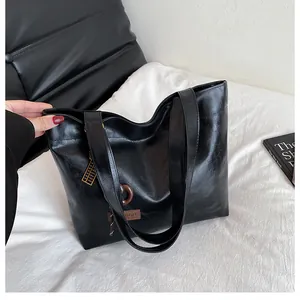 Détail du sac cabas noir brillant avec texture en cuir et étiquette de mode marron