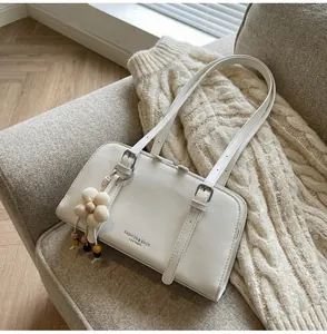 Close-up of white leather tote with silver buckles and a knit flower charm detail
