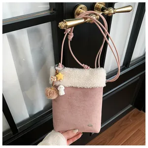 Détail du petit sac rose en suédine avec bordure en peluche et pendentifs mignons