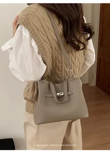 Detailed view of the sleek silver metal lock and folding flap on grey leather bucket bag