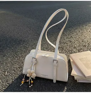 Detail of white leather tote bag with floral pendant and silver buckle on outdoor pavement