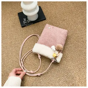 Détail du sac bandoulière en suédine rose avec bordure en peluche blanche et jolis porte-clés