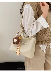 Close-up of retro cream leather bucket bag with silver lock and plush bear charm