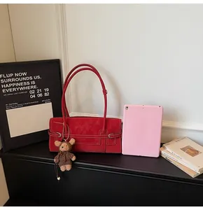 Macro shot of red suede tote with white contrast stitching and a cute bear charm
