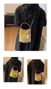 Detail of light green suede bucket bag with leather handles and a cute bunny charm