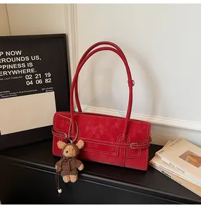 Detail of red vintage leather tote bag with decorative buckle and plush bear pendant