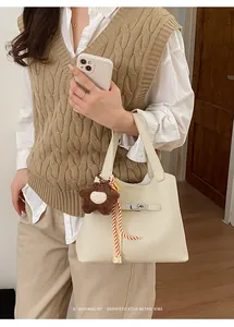 Detail of cream bucket bag with silver clasp, plush star charm and striped silk scarf
