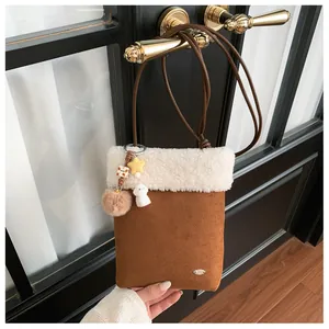 Détail d'un sac bandoulière d'hiver avec bordure peluche et breloques sur une porte