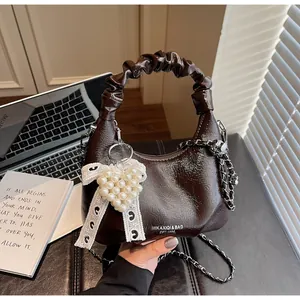 Detail view of mini chocolate pleated handbag featuring pearl heart and lace bow accent
