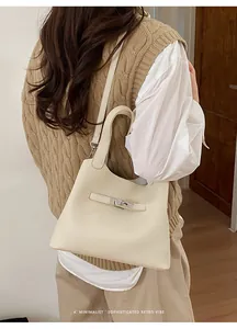 Creamy white litchi pattern leather bucket bag shown on a model in a minimal interior