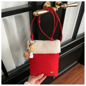 Détail du sac bandoulière en daim rouge avec bordure pelucheuse et charme de chiot