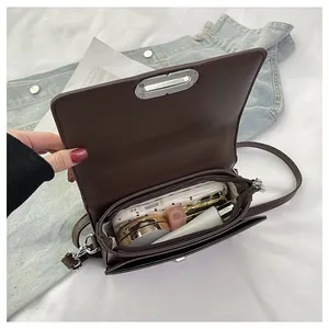 Internal view of brown crossbody bag showing storage for phone, lipstick, and makeup