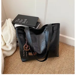 Gros plan d'un sac cabas noir avec texture lisse et détail d'étiquette en cuir marron