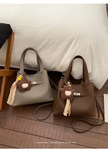 Detail of lychee pattern leather bucket bags in gray and brown with cute charms