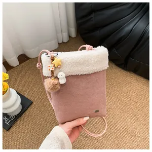 Détail du sac bandoulière rose en daim avec bordure en peluche et breloques mignonnes