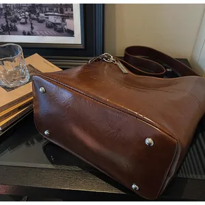 Detailansicht des braunen Taschenbodens aus Leder mit Metallfüßen und Markenprägung