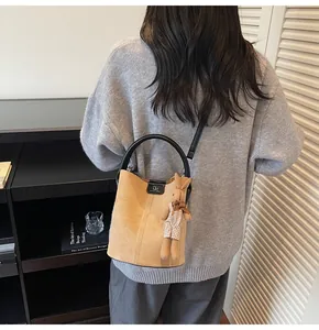 Detail of light brown suede bucket bag with RM logo and cute plush rabbit charm