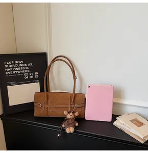 Close-up of brown vintage leather bag with silver buckle and cute plush bear charm