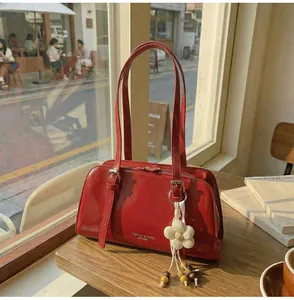Close-up of a red glossy patent leather shoulder bag with a knit flower charm detail