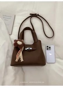Detail of dark brown lychee leather bucket bag with silver lock and sunflower charm