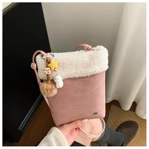 Détail du sac bandoulière rose en daim avec bordure peluche blanche et breloque chien