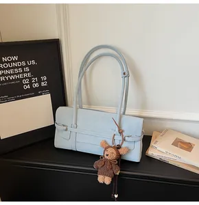 Close-up of light blue rectangle faux leather tote bag with cute brown teddy bear charm