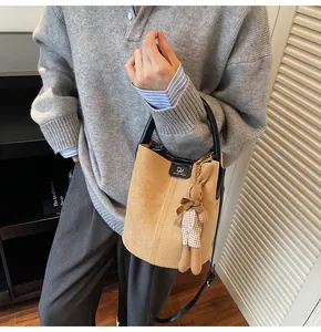 Detail view of brown faux suede bucket bag with a cute rabbit plush charm and black handle