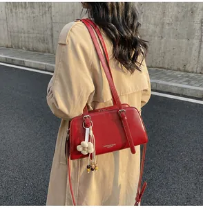 Macro shot of red glossy leather shoulder bag with silver hardware and flower pendant