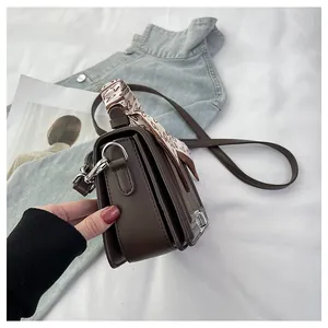 Detail view of coffee leather square bag with pleated sides and heart pattern scarf