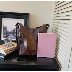 Detailansicht der braunen Leder-Shopper-Tasche mit Logo-Prägung und Taschenanhänger