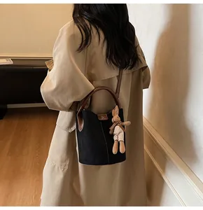 Black bucket bag with brown leather ring handle and a cute rabbit charm shown on model
