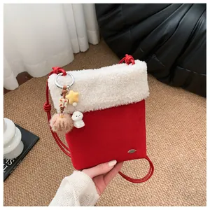Détail d'un sac bandoulière rouge avec bordure en peluche et charm de poupée