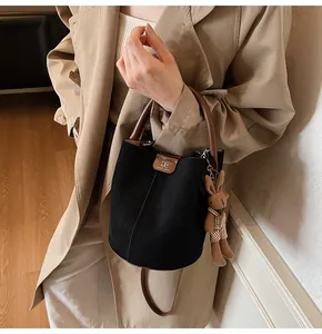 Close-up of black suede bucket bag with brown leather handle and cute rabbit charm