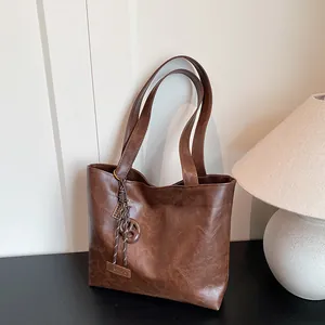 Grand sac cabas marron en cuir avec étiquette FASHION et pendentif sur un bureau