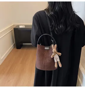 Detail of dark brown suede bucket bag with black handle and cute rabbit charm