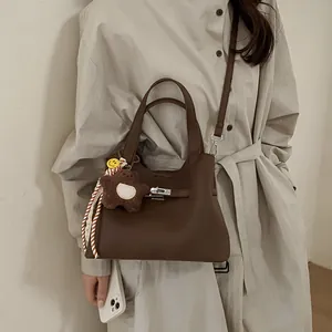 Retro dark brown leather bucket bag with top handles and a cute plush charm on a model