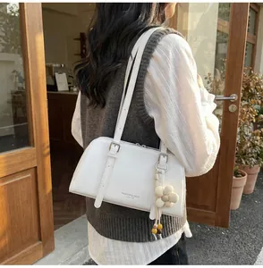 Detail of cream PU leather tote bag with daisy pendant shown in a street cafe setting