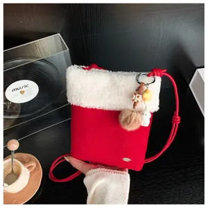 Détail du sac bandoulière en peluche rouge avec bordure en fausse fourrure blanche et breloque