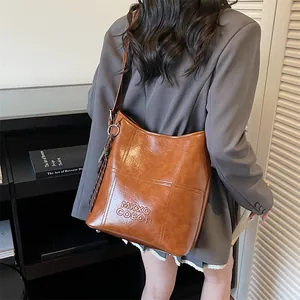 Braune Vintage-Eimer-Tasche aus Leder mit Logo-Prägung für den täglichen Arbeitsweg