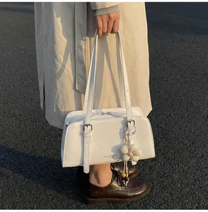 Close-up of white leather tote bag with silver buckle and woven flower charm detail