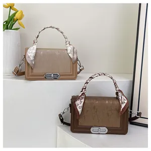 Detail of square crossbody bags with textured stripes and decorative silk scarf handle
