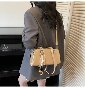 Detail of beige leather tote bag with wood bead tassel shown on a model in gray blazer