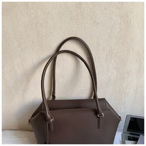 Détail du sac cabas marron foncé montrant le motif de litchi et les anneaux argentés