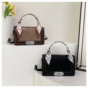Detail of square crossbody bags with textured flaps and silk scarves on white stands