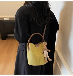Detail of green suede bucket bag with round brown handle and plush bunny charm