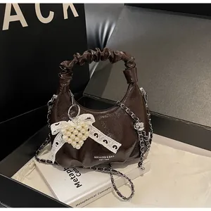 Detail of coffee brown pleated handbag with pearl heart charm and metal chain strap