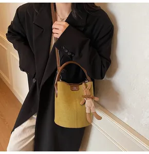 Detail of mustard yellow suede bucket bag with leather handles and cute rabbit charm