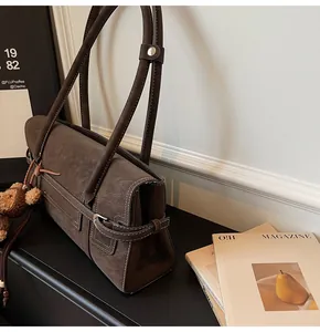 Detail of vintage brown shoulder bag with white contrast stitching and plush bear charm