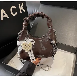 Detail view of dark brown patent leather hobo bag with lace pearl heart bow accessory