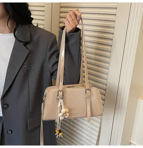 Detail of beige faux leather tote bag with floral charms and double zipper closure